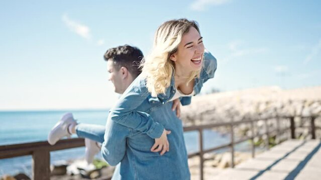 Man and woman couple smiling confident holding girlfriend on air turning at seaside