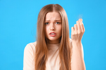 Worried young woman with hair loss problem on blue background