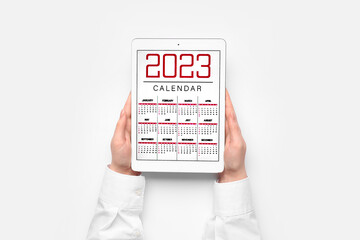 Woman holding tablet computer with calendar on white background
