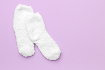 Pair of warm white socks on lilac background