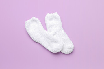 Pair of warm white socks on lilac background