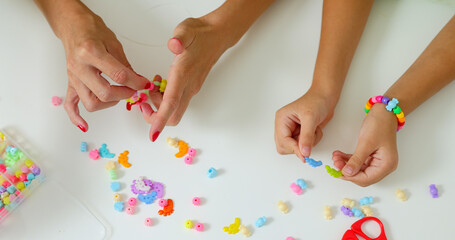 Little girls putting beads together in bracelet. Child's handicraft concept. 