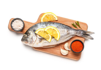Wooden board with raw dorado fish, lemon and spices on white background
