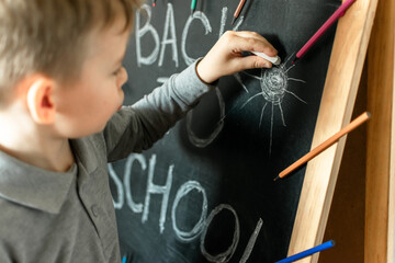a little boy writes with chalk on a blackboard. the child learns to write. preparation for school. early development
