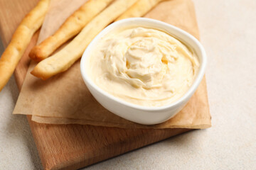 Bowl with tasty cream cheese on light background