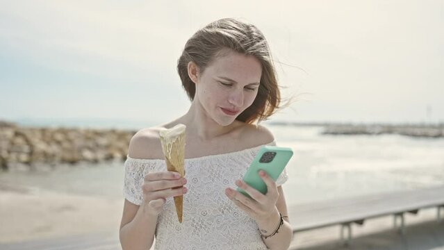 Young blonde woman tourist holding ice cream make selfie by smartphone at seaside