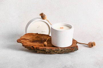 Holders with candles and tree bark on white background