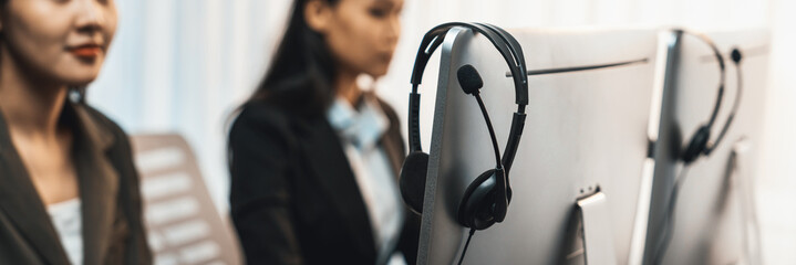 Panorama focus headset on call center workspace desk with blur background of operator team or telesales representative engage in providing client with customer support service or making sales. Prodigy