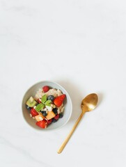 Sliced Fruits in a Bowl Near a Gold Spoon on a White Surface   