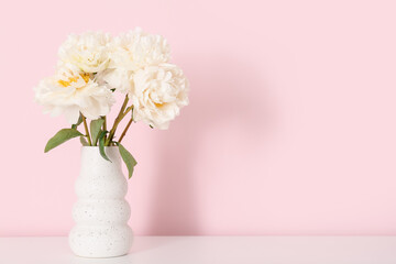 Vase of white peonies on dresser near pink wall