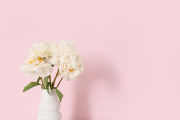 Vase of white peonies on pink background