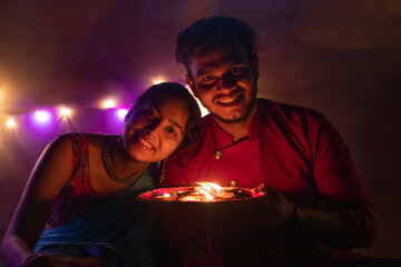 Portrait of couple with tray of diyas on diwali