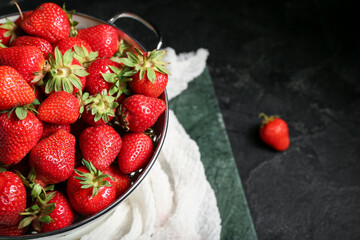 Colander with fresh strawberries on black background