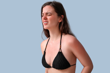 Allergic young woman with sunburned skin on blue background