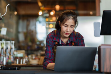 Closeup of store owner smiling when typing on laptop computer Because they are responding to...