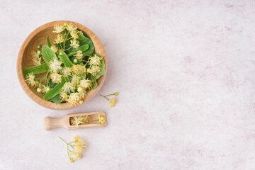 Wooden bowl with fresh linden flowers on light background