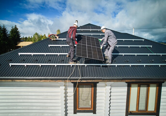 Male workers installing solar cell on a roof. Solar system installation on top of house. Two men...