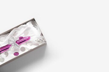 Gift box with vibrator and confetti on white background