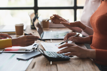 Confident group of young businesswoman analyzing data using laptop computer brainstorming meeting to analyze financial reporting situation and point to documents, profit charts, growth graphs.