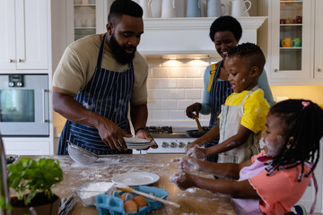 African american children playing with flour while parents making pancakes in kitchen