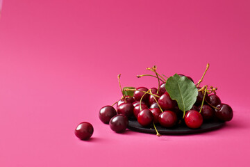 Board with sweet cherries on pink background