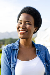 Portrait of happy african american woman on sunny terrace