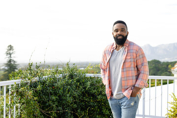 Portrait of happy african american man staying on sunny terrace with copy space