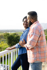 Happy african american couple embracing and staying on sunny terrace