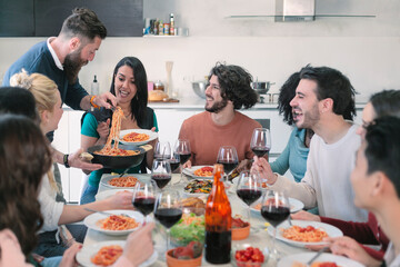 Happy group of friends eating pasta at home dinner party - Cheerful young people having lunch break together - concept