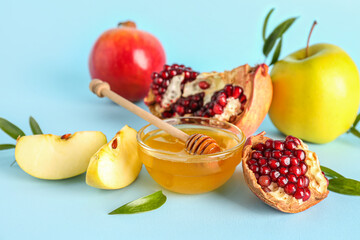 Bowl of honey, pomegranate and apples for Rosh Hashanah celebration (Jewish New Year) on blue background