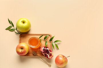 Wooden board with jar of honey, pomegranate and apples for Rosh Hashanah celebration (Jewish New Year) on beige background