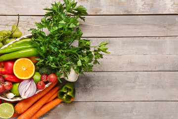 Wicker bowl with different fresh fruits and vegetables on grey wooden background