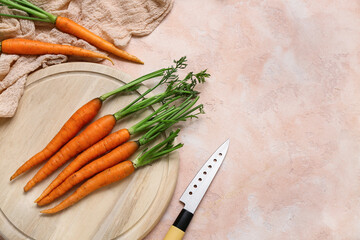 Tasty fresh carrots and wooden board on orange textured background