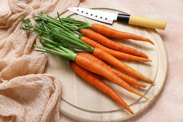 Fresh carrots with wooden board on orange textured background