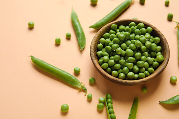 Bowl with fresh green peas on orange background