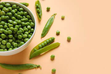 Bowl with fresh green peas on orange background