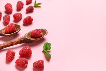 Spoons with fresh raspberries and mint on pink background