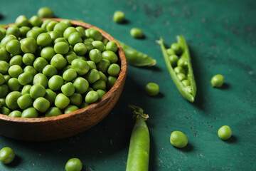 Bowl with fresh green peas on color background