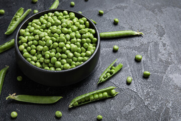 Bowl with fresh green peas on black background
