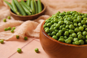 Bowls with fresh green peas on pink tile table