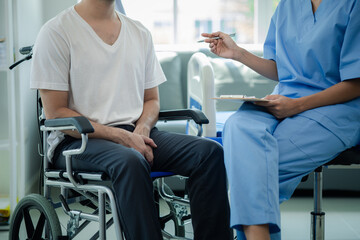 Male patient sitting in wheelchair undergoing a medical examination with specialist physician,...