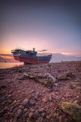 Old rusty fishing boat on the beach at sunset in Batam Indonesia - 618728889
