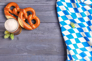 Flag of Bavaria, mug with beer and pretzels on blue wooden background