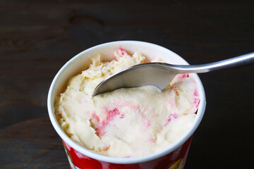Spoon scooping delectable creamy strawberry cheesecake ice cream