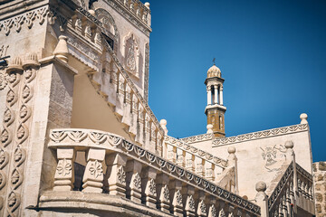 Belltower of Bethil Church and stone carved balustrades of traditional building at Midyat....