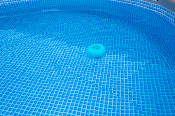 natural light. frame pool. a container with solid tablets floats in the pool for disinfection.
