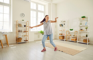 Fototapeta na wymiar Full body photo of young happy smiling girl wearing casual clothes dancing in the living room at home. Beautiful woman having fun with a satisfied face expression. People emotions concept.