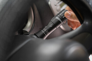 Naklejka premium Woman hand use turn signal switch, close-up. Turning car lights