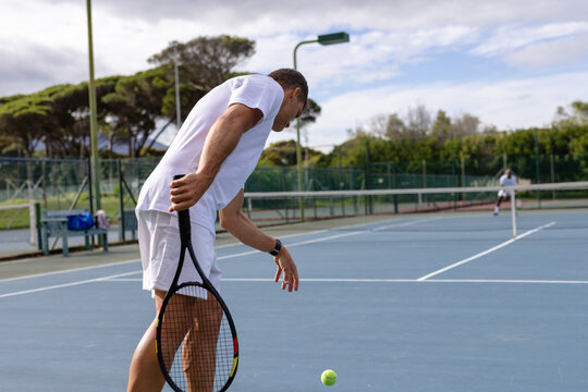 Diverse male tennis players playing tennis on outdoor court, copy space