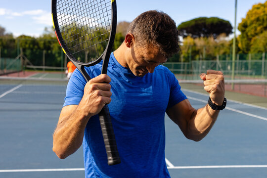 Caucasian male tennis player celebrating victory on outdoor court on sunny day